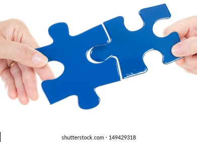 People Putting Two Pieces Of Jigsaw Together