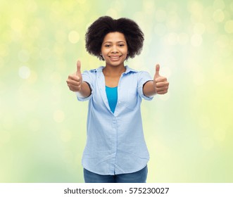 people, race, ethnicity, gesture and portrait concept - happy african american young woman showing thumbs up over summer green lights background