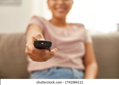 People, Race, Ethnicity And Portrait Concept - Happy Smiling African American Young Woman With Remote Control Watching Tv At Home