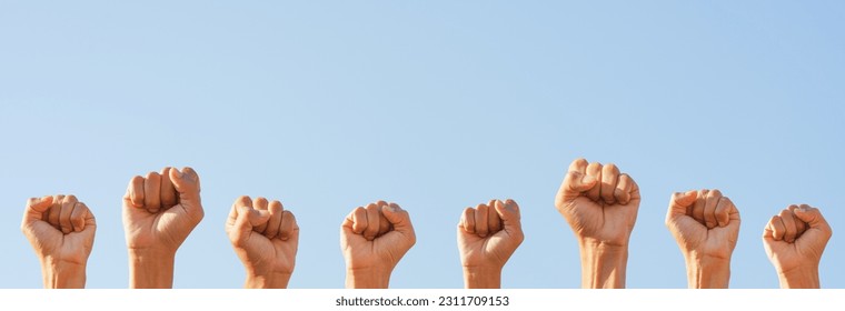 People raise fists, sky background. Power of teamwork and Competition concept - Shutterstock ID 2311709153