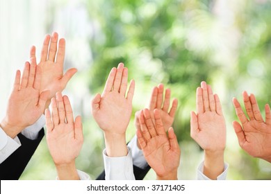 People Raise Their Hands Up To Be Picked Up Or To Bid In An Auction Over Green Background