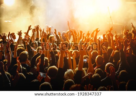 People with raised hands at a public event. Gathering in concert hall