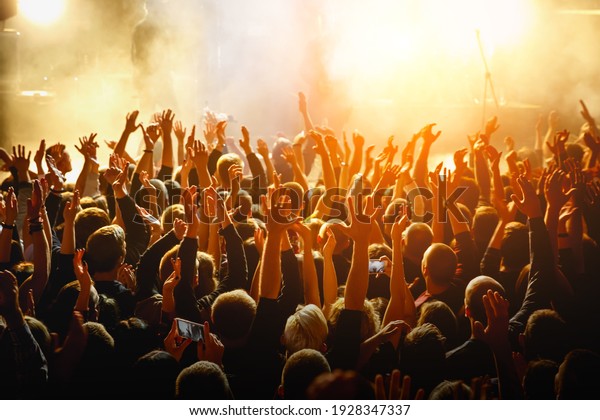 People with raised hands at a public event.\
Gathering in concert\
hall