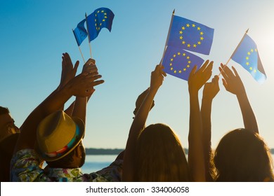 People With Raised Hands Waving Flags Of The European Union. European Dream. Future Of Europe. European Flag. Fans From Europe Rooting For Their Team.