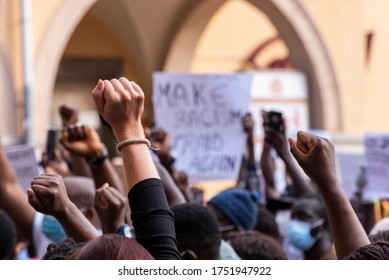 People raising fist with unfocused background in a pacifist protest against racism demanding justice - Powered by Shutterstock