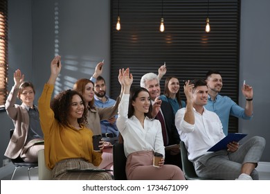 People Raising Hands To Ask Questions At Seminar In Office