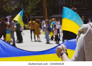 People at rally in support of Ukraine affected by Russia. Patriots with yellow blue Ukrainian flags. Stop Putin, hands off Ukraine, Save Mariupol. Protestors in defocus. War in Ukraine. Social issues.