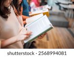 People reading books in a library. Diverse group, books in hand, reading together. Focus on reading, books, and learning in a library setting. Asian young woman reading a book.