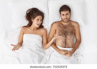 People, Relationships Problems, Crisis, Divorce And Separation Concept. Frustrated Youple Couple Experiencing Financial Difficulties. Angry Jealous Female Nagging At Her Stressed Out Husband In Bed