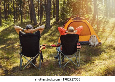 people relaxing in camping chairs at forest campsite and enjoying the nature - Powered by Shutterstock