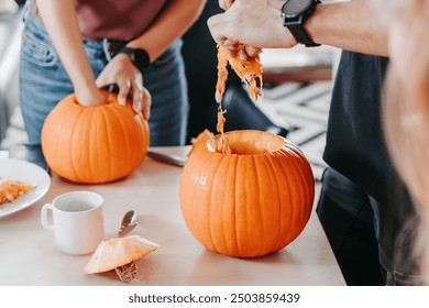 People removing seeds and pulp from pumpkins while preparing for Halloween carving, workshop - Powered by Shutterstock