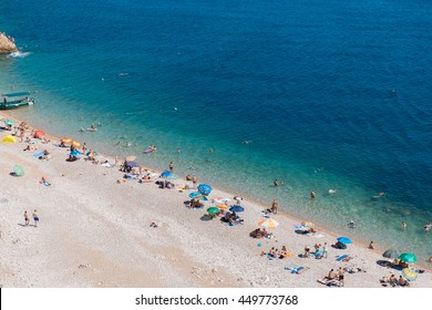 People Rest On The Sea Beach With Blue Water In Crimea