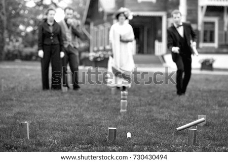 People in retro fashion cloth play outdoor game of Edwardian period. Historical reconstruction of vintage soir.