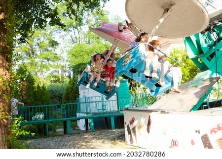 People ride a carousel in the amusement park.Parents with children have fun in the park on carousels