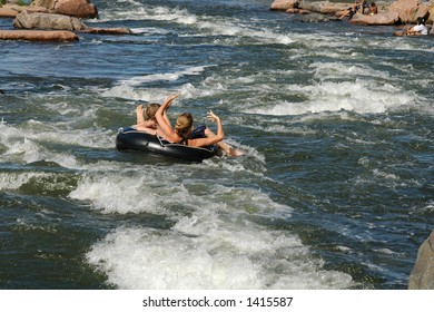 People Ride An Inner Tube Down The River Rapids