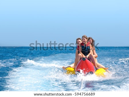 People ride on banana boat. Bright blue sea and clear sky. Happy vacations.