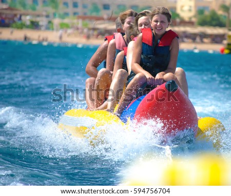 People ride on Banana boat on sunny summer day. Beach water sport