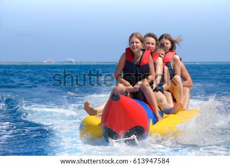 People ride on banana boat. Bright blue sea and clear sky. Happy vacation. Beach water sport