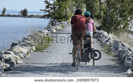 people riding a bike on the colchester causeway gravel bike path in burlington, vermont (mountain bikes with kid's bike) from behind, unrecognizable (sport, recreation, travel, bike riding, cycling) [[stock_photo]] © 