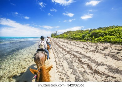 People Riding On Horse Back At The Caribbean Beach. Grand Cayman.