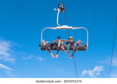 People riding ski chairlift. View from below. Group of people traveling on ski lift on top of mount for enjoing ski and snowboard. Winter sport, travel and vacation concept.