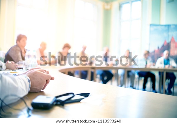 People at a round table discuss different issues.\
Focus on hand