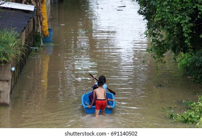People rowing a boat through a flooded street in Thailand                               