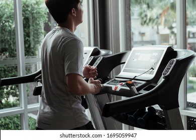 People Running In Machine Treadmill At Fitness Gym. Young Man Running On A Treadmill At Home. Male Athlete Workout On Running Exercise Machine.