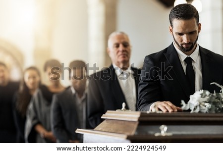People, sad and funeral coffin, death and grief in church during ceremony or service, depression or floral. Support, emotional pain and sorry with casket, mourning and man in suit at casket in chapel