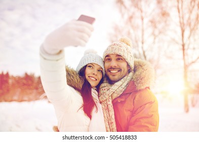 people, season, love, technology and leisure concept - happy couple taking selfie by smartphone over winter background - Powered by Shutterstock