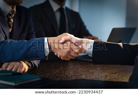 People shaking hands in a dark room. Corruption. Collusion.