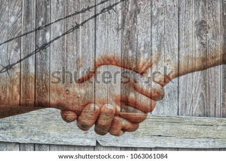 People shaking hands with fence on vintage wooden board wall background.A symbol sign of world war peace,harmony,tranquil,calm.Concept of Internationnal Peace Day.Korean peace. 