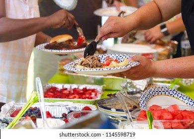 People Sharing Food At A Summer Potluck Event