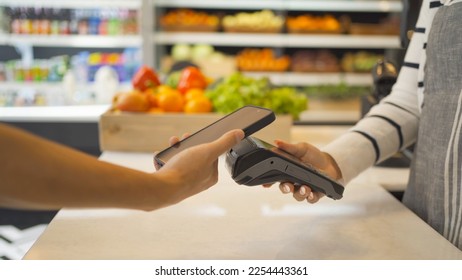 People shopping in a supermarket or retail shop, buying snacks and food by online credit card on mobile phone in cashier on grocery products shelves. Food shopping. People lifestyle.  Checkout service - Powered by Shutterstock