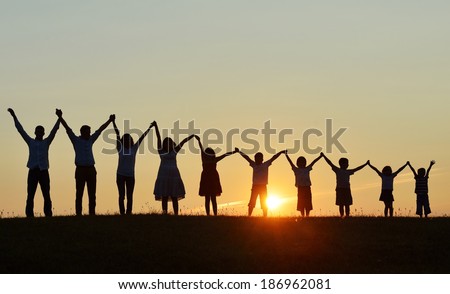 People silhouettes on sunset meadow having fun