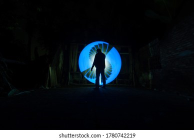 People Sillhouette Standing Alone With Blue Circle Light Painting As The Backdrop