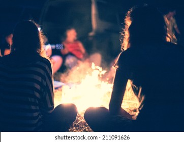 People sit at night round a bright bonfire - Shutterstock ID 211091626