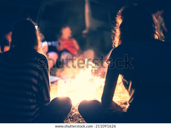 People sit at night\
round a bright bonfire