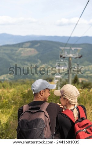 People sit on the ski elevator. View from the back. Summer, green forest. summer family vacation in the mountains.