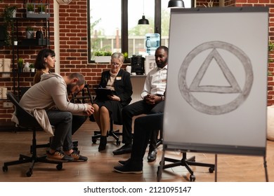 People Sitting In Circle At Group Therapy Session While Having Aa Meeting Sign In Office. Patients With Alcohol Addiction Having Conversation About Mental Health Problems And Issues.