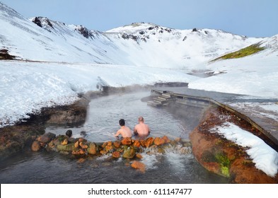 People sitting in Hot river in Iceland in winter snowy mountains - Powered by Shutterstock