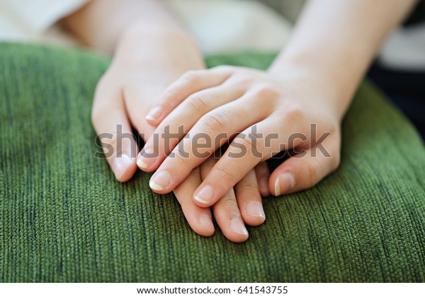 People sitting relax together\
with hands clasped on green pillow closeup soft focus blur\
background