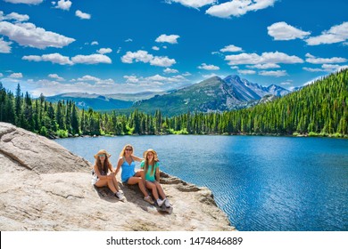 People Sitting And Relaxing By The Lake. Smiling Family Enjoying Time Together On Hiking Trip. Beautiful Summer Mountain Landscape. Bear Lake, Rocky Mountains National Park, Colorado ,USA.