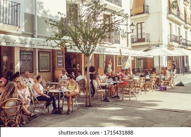 People sitting at a summer outdoor cafe, joyful of talking and relaxing on Ibiza old town. Ibiza, Spain, 20 August 2019 