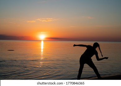 People Skipping Stones During Sunset. People Siluets During Golden Hour. Estonian Beach During Mid Summer Fest. Doing Sports During Sunset. Skipping Competition. Colorful Sunset