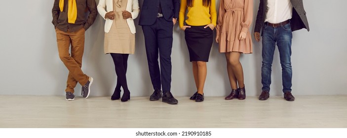 People in smart casual clothes by office wall. Row of company employees in pants, skirts, jackets and jumpers of brown, yellow, dark blue, beige color. Low section legs. Work dress code concept - Powered by Shutterstock