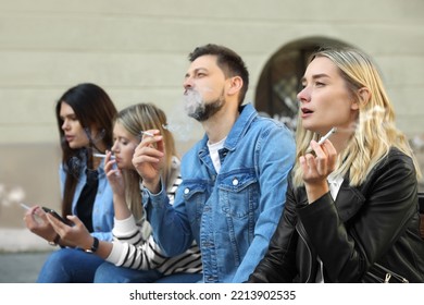 People smoking cigarettes at public place outdoors - Powered by Shutterstock