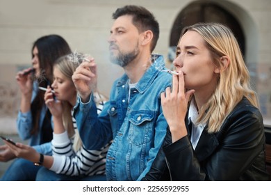 Gente fumando cigarrillos en un lugar público al aire libre