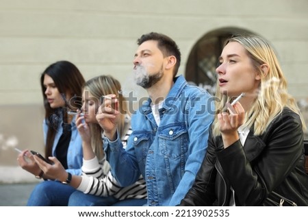 People smoking cigarettes at public place outdoors