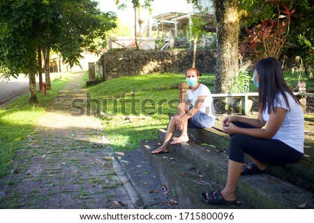 People social distancing while wearing mask.Neighbours with facemask gossiping in the outdoor.Corona Virus pandemic.